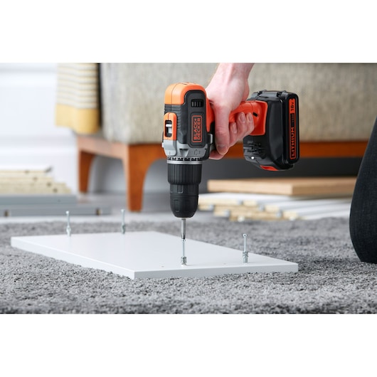 Perceuse sans fil BLACKDECKER BCD003C1 assemblant panneau blanc sur tapis.