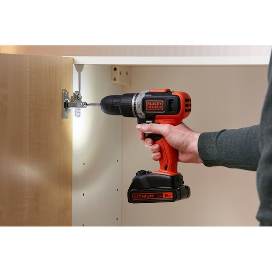 Photo de la perceuse sans fil BLACK+DECKER BCD003C2K utilisée pour installer une charnière dans une armoire.