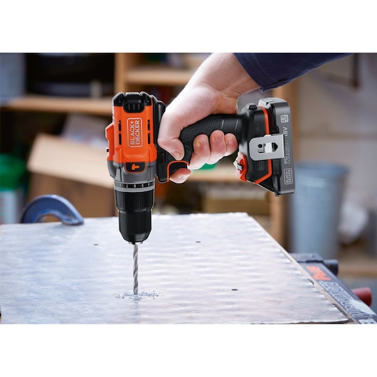 Foto van de BLACK+DECKER BCD383D1 snoerloze boormachine in gebruik bij het boren in een metalen plaat, close-up.
