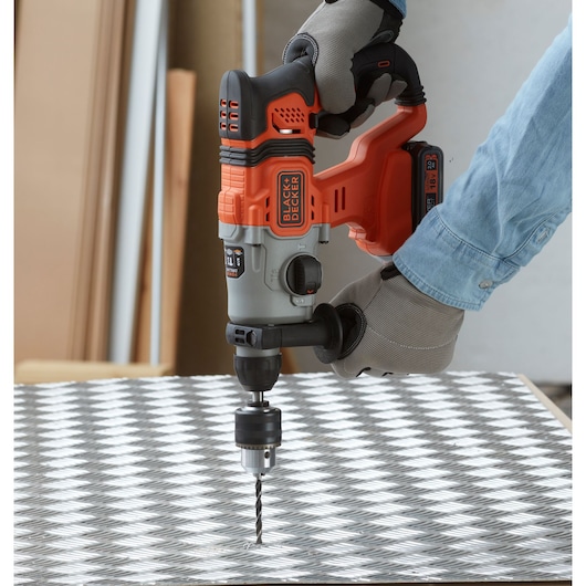 BLACK+DECKER BCD900B draadloze klopboormachine in gebruik op een metalen plaat met patroon, close-up.