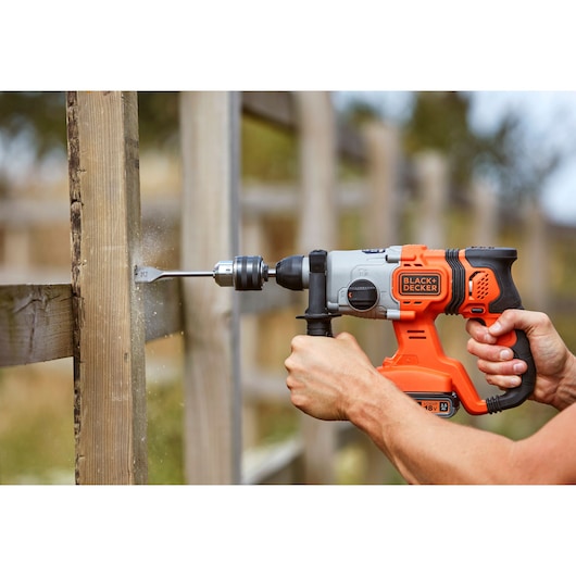 Photo de la perceuse à percussion sans fil BLACK+DECKER BCD900E2K utilisée pour percer du bois en extérieur.
