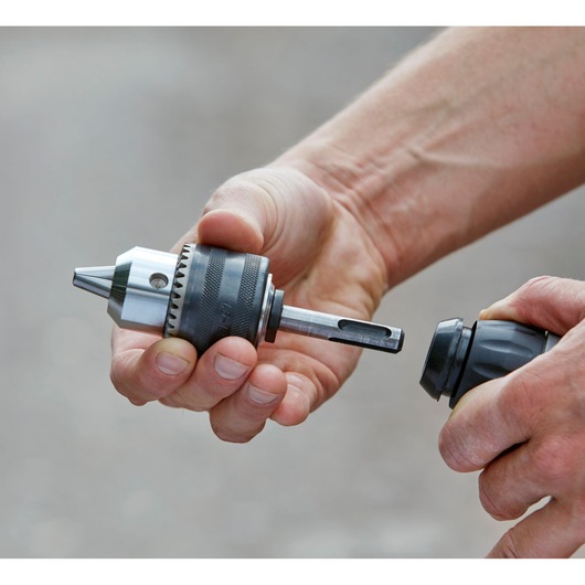 Accessoire mandrin pour perceuse à percussion BLACKDECKER BCD900E2K en cours d'installation, gros plan sur les mains.
