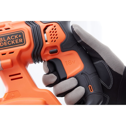 Photo gros plan de la poignée de perceuse sans fil BLACK+DECKER BCD900E2K, orange et noire, tenue par une main gantée.