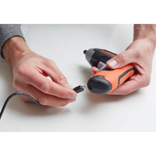 Photo du tournevis sans fil BLACKDECKER BCF611CK en cours de charge avec un câble USB, gros plan sur fond blanc.