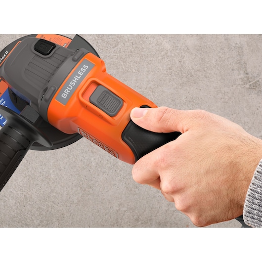 Close-upfoto van een hand die de BLACKDECKER BCG6L8N accu-haakse slijper met brushless motor bedient.