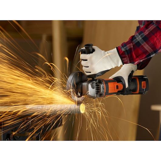 Foto van BLACKDECKER BCG720M1 draadloze haakse slijper die een metalen buis doorslijpt, met vonken.
