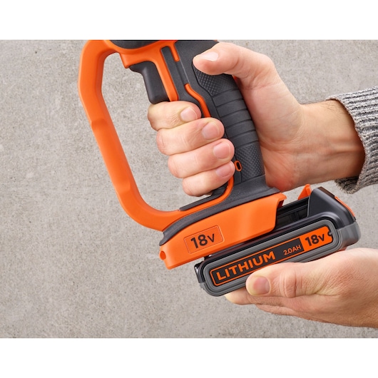 Foto van BLACKDECKER BCG720M1 handgreep met oranje 18V lithium 2.0Ah accu, hand houdt het gereedschap vast.