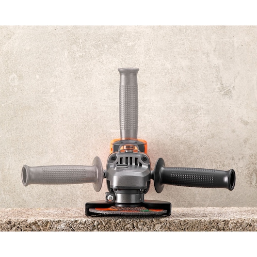 BLACK+DECKER BCG720M1 haakse slijper frontaal op betonnen oppervlak, drie-positie handgreep, zilver en zwart.