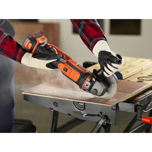 BLACKDECKER BCG720N haakse slijper in gebruik, tegels snijden, close-up, gebruiker met handschoenen.