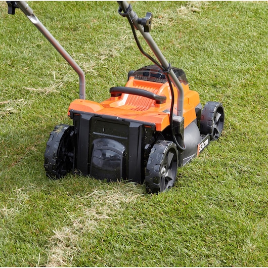BLACKDECKER BCMW3318N tondeuse gros plan sur herbe, carrosserie orange et noire, vue arrière.