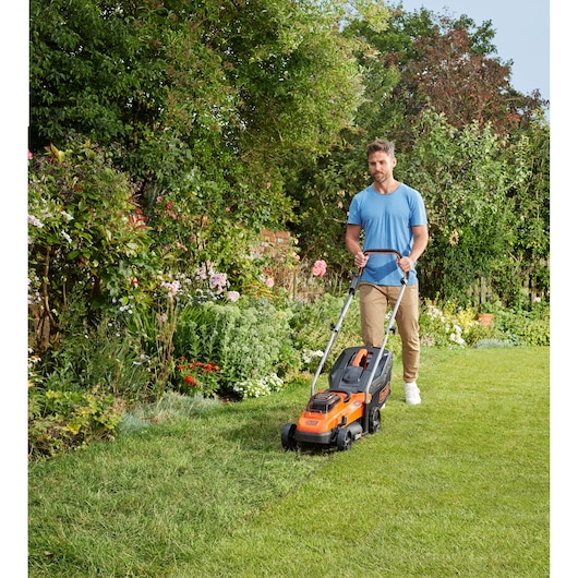 Photo de la tondeuse BLACKDECKER BCMW3336N utilisée sur pelouse dans un jardin.