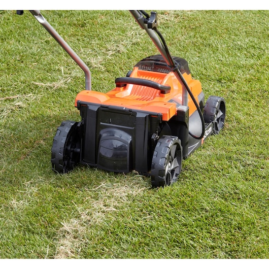BLACKDECKER BCMW3336N tondeuse arrière sur gazon, corps orange et noir, grandes roues.