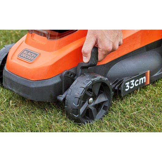 BLACK+DECKER BCMW3336N tondeuse vue latérale, main réglant la hauteur de la roue, orange et noir, largeur de coupe 33cm.