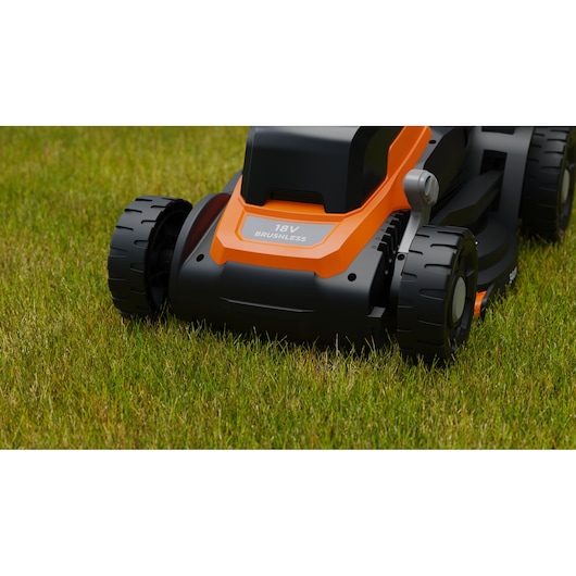 Close-up van een oranje-zwarte BLACK+DECKER draadloze brushless grasmaaier op groen gras.
