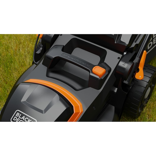 Close-up van een BLACK+DECKER grasmaaier, met de nadruk op het handvat, de bedieningsknop en merkdetails, geplaatst op een grasveld.