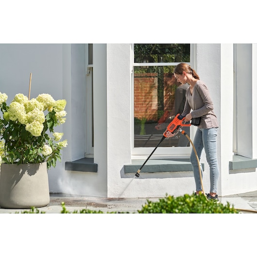 Foto van BLACKDECKER BCPC18B hogedrukreiniger die buitentegels schoonmaakt bij een wit huis.