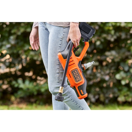 BLACKDECKER BCPC18B draadloze hogedrukreiniger vastgehouden door persoon buiten.