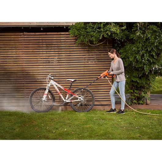 Foto van BLACK+DECKER BCPC18D1 hogedrukreiniger die buiten een mountainbike schoonmaakt.
