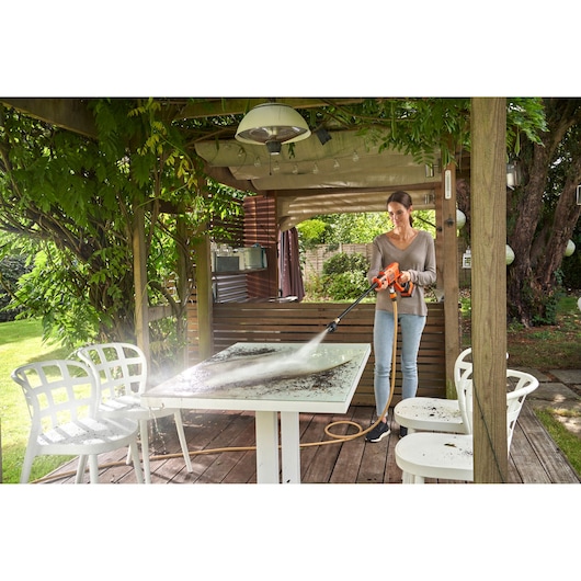 BLACKDECKER BCPC18D1 hogedrukreiniger reinigt een terrastafel onder een houten pergola.
