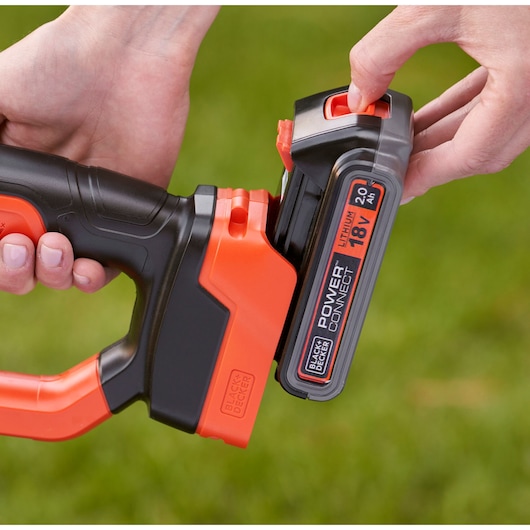 Close-up van BLACKDECKER BCPC18D1 18V lithium batterij die op een snoerloos gereedschap buitenshuis wordt bevestigd.