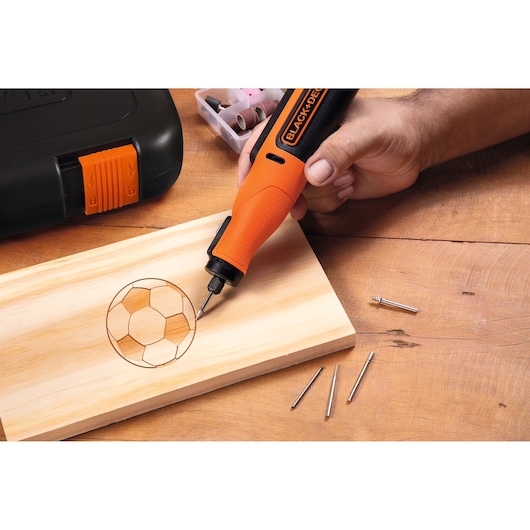 BLACK+DECKER BCRT8IK roterend gereedschap graveert voetbalontwerp op hout, accessoires en koffer zichtbaar.