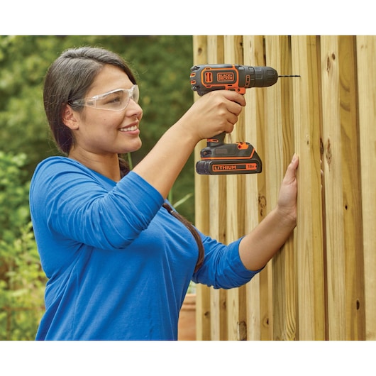 Perceuse sans fil BLACKDECKER BDC718AS2O utilisée pour percer une clôture en bois en extérieur.