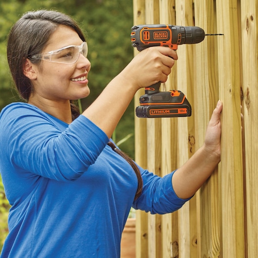 Photographie de BLACKDECKER BDCDC18KB perceuse sans fil utilisée pour percer du bois clair en extérieur.