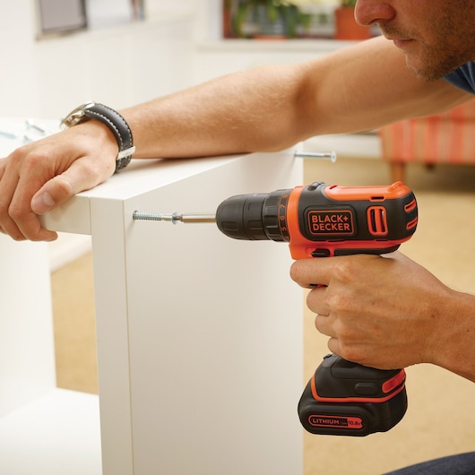 BLACKDECKER BDCDD12B perceuse sans fil utilisée pour assembler des meubles blancs en intérieur.