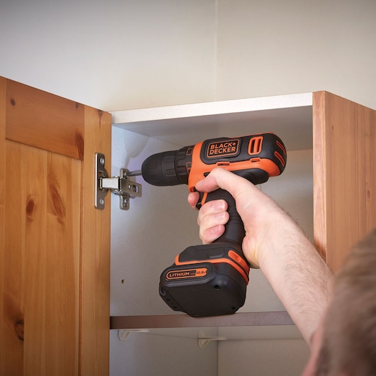 BLACKDECKER BDCDD12B perceuse sans fil utilisée pour assembler une armoire en bois, tenue à la main.