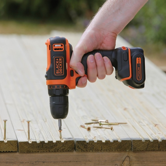 BLACKDECKER BDCDD12B perceuse sans fil utilisée pour visser dans des planches en bois en extérieur.