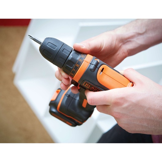 Photographie de la perceuse sans fil BLACKDECKER BDCDD12 orange et noire tenue en main.