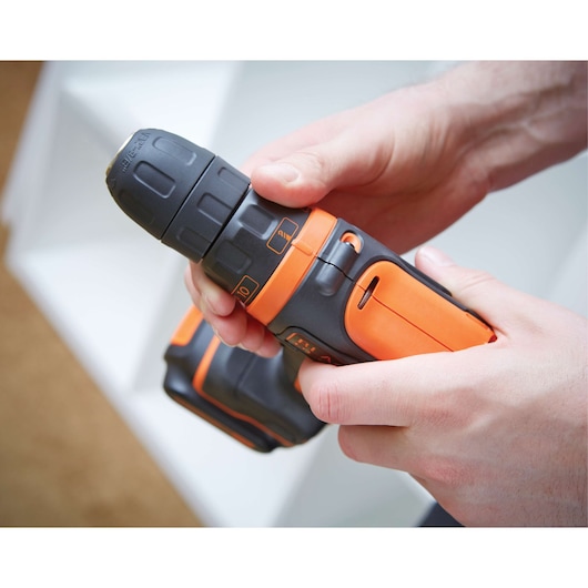 Perceuse sans fil BLACKDECKER BDCDD12 orange et noire tenue en main, photographie en gros plan.