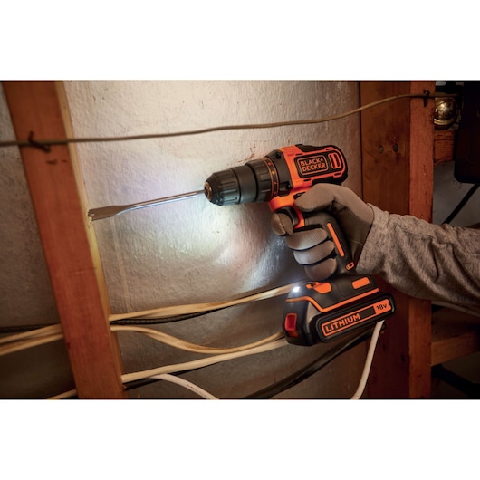 Perceuse-visseuse sans fil BLACK+DECKER BDCDD186B en utilisation, perçant du bois, batterie lithium 18V visible.