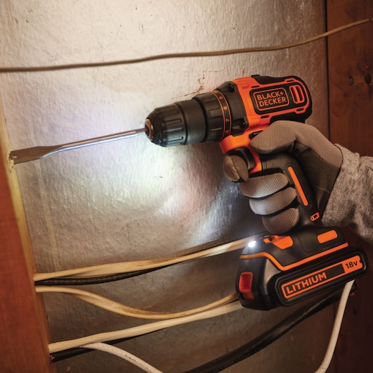 Photo d’une perceuse sans fil BLACK+DECKER BDCDD186KB avec batterie lithium 18V utilisée près de fils électriques.