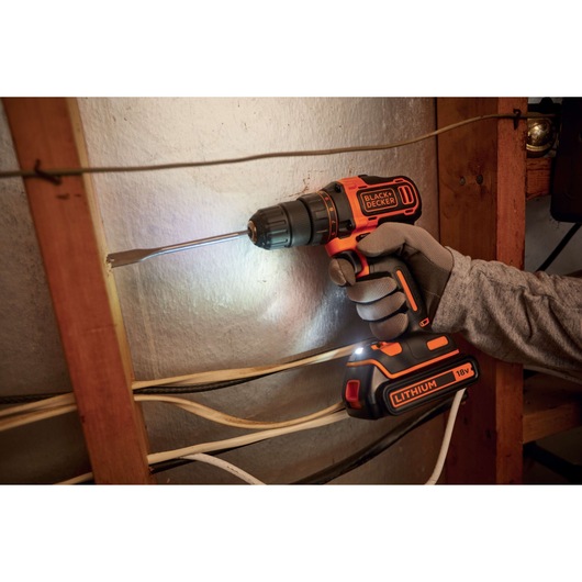 BLACK+DECKER BDCDD186K accuboormachine met 18V lithiumbatterij in gebruik op een muur, gebruiker draagt handschoenen.