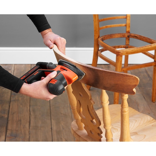 BLACKDECKER BDCDS18 ponceuse sans fil utilisée sur chaise en bois, angle rapproché.