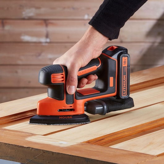 BLACKDECKER BDCDS18 ponceuse mouse sans fil avec batterie lithium ponçant une surface en bois, gros plan.