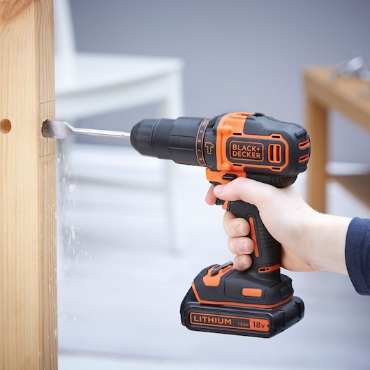 Photographie d'une BLACKDECKER BDCHD18KB perceuse sans fil utilisée pour percer un trou dans du bois.