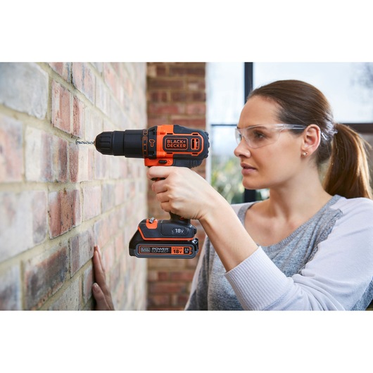 Photo de la perceuse sans fil BLACK+DECKER BDCHD18S2KA utilisée pour percer un mur en briques.