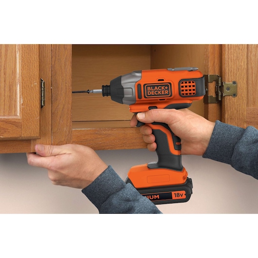BLACKDECKER BDCIM18N slagschroevendraaier gebruikt om een schroef in een houten kast te plaatsen.
