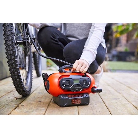 BLACKDECKER BDCINF18N draagbare luchtcompressor gebruikt om een fietsband buiten op te pompen.