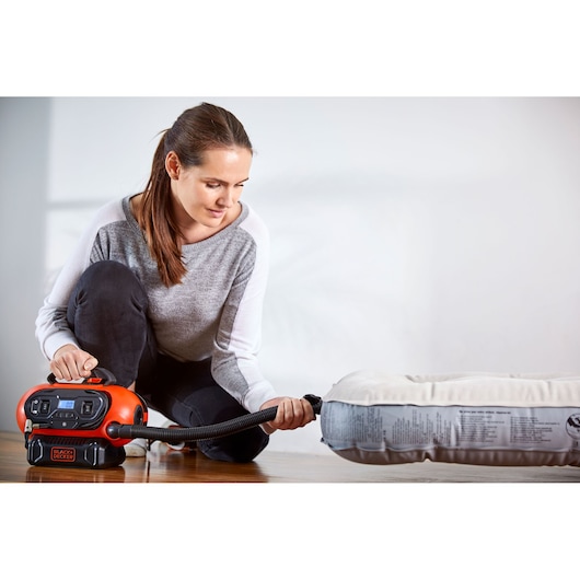 BLACKDECKER BDCINF18N luchtpomp gebruikt om matras binnenshuis op te blazen, product in gebruik met slang.