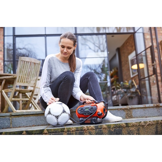BLACKDECKER BDCINF18N draagbare luchtpomp naast een voetbal buiten, product in gebruik.