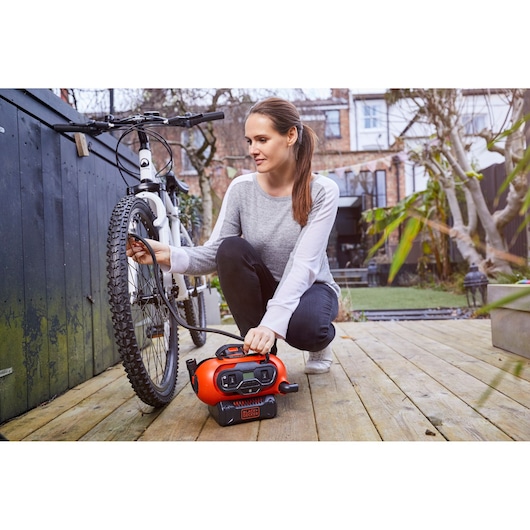 BLACKDECKER BDCINF18N draagbare luchtpomp wordt gebruikt voor het oppompen van een fietsband op een houten vlonder.