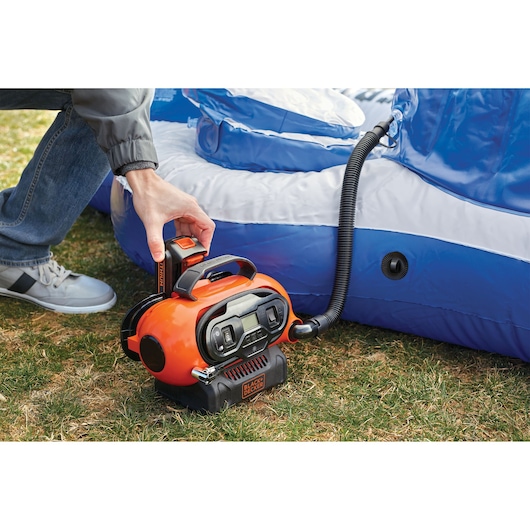 BLACKDECKER BDCINF18N draagbare inflator wordt gebruikt om een blauw-wit zwembad buiten op te blazen.