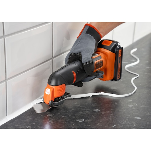 BLACKDECKER BDCOS18D1K outil multifonction oscillant sans fil utilisé pour enlever le mastic au bord d'un plan de travail.