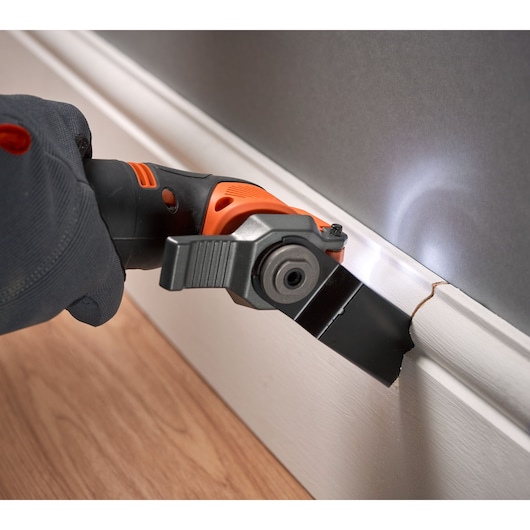 BLACKDECKER BDCOS18N oscillerend gereedschap snijdt witte plint met LED-licht, close-up actie.
