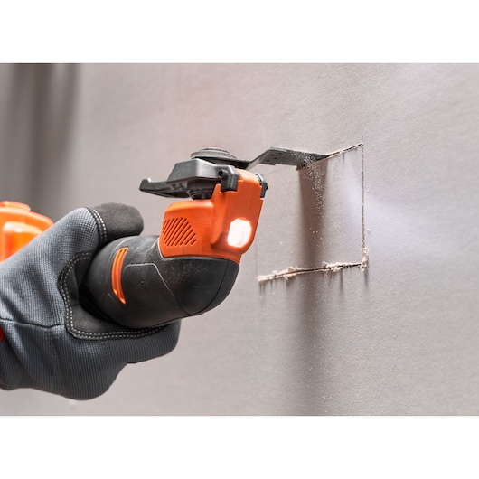 BLACKDECKER BDCOS18N oscillerend gereedschap snijdt een vierkant in gipswand, close-up fotografie.