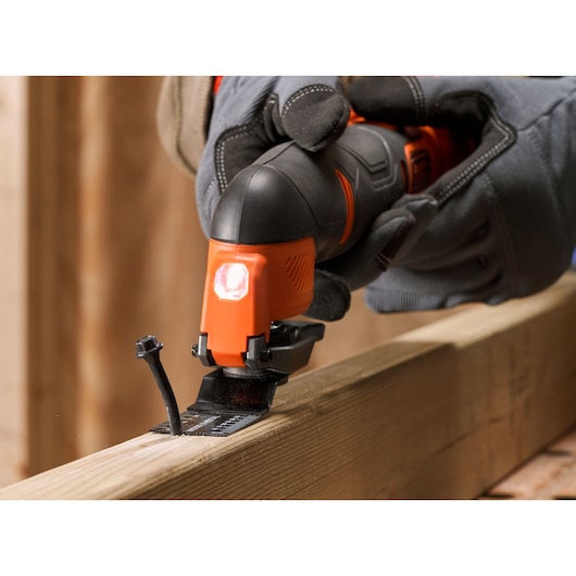 BLACKDECKER BDCOS18N oscillerend multitool snijdt hout, close-up met handschoen, bouwomgeving.