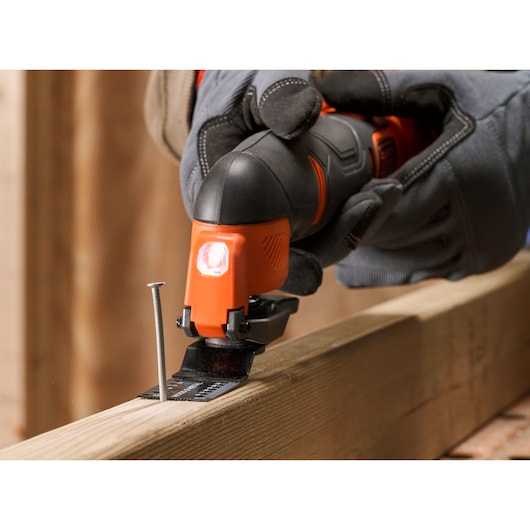 BLACKDECKER BDCOS18N oscillerend multitool zaagt hout naast een spijker, detailfoto tijdens gebruik.